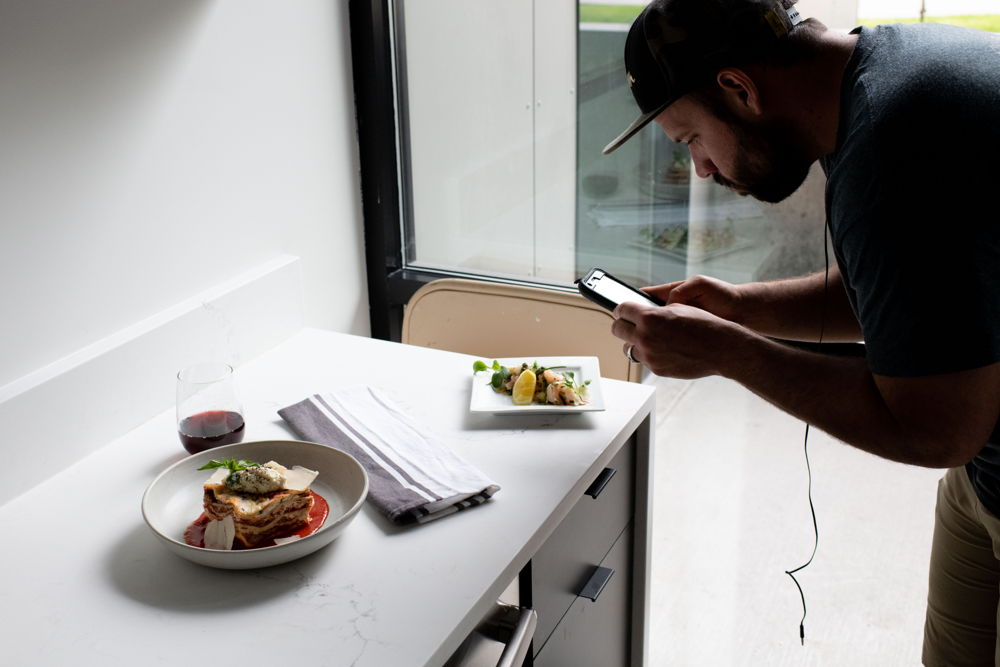 A chef photographing plated dishes by a window
