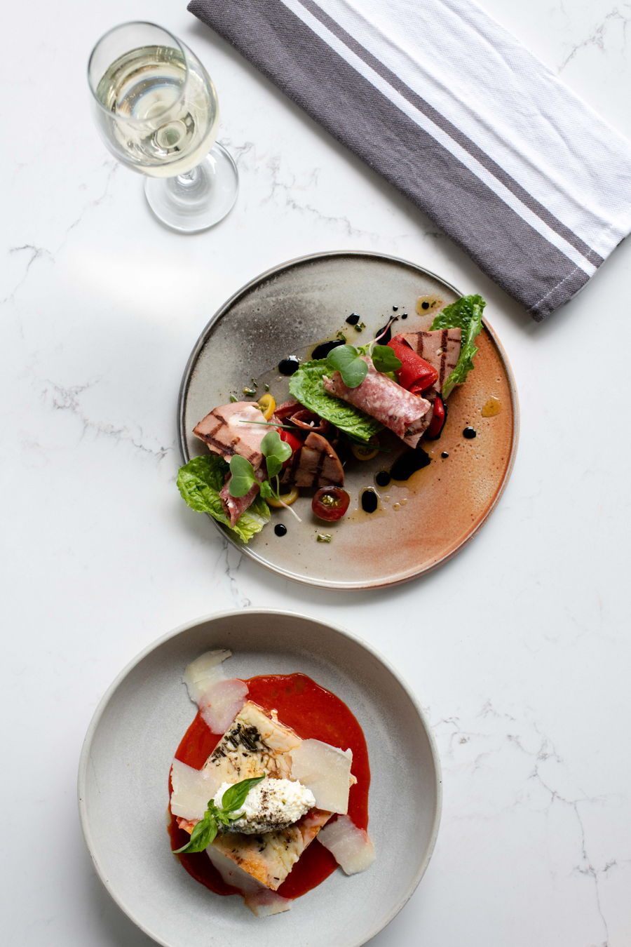 Plated dishes and a glass of wine on marble
