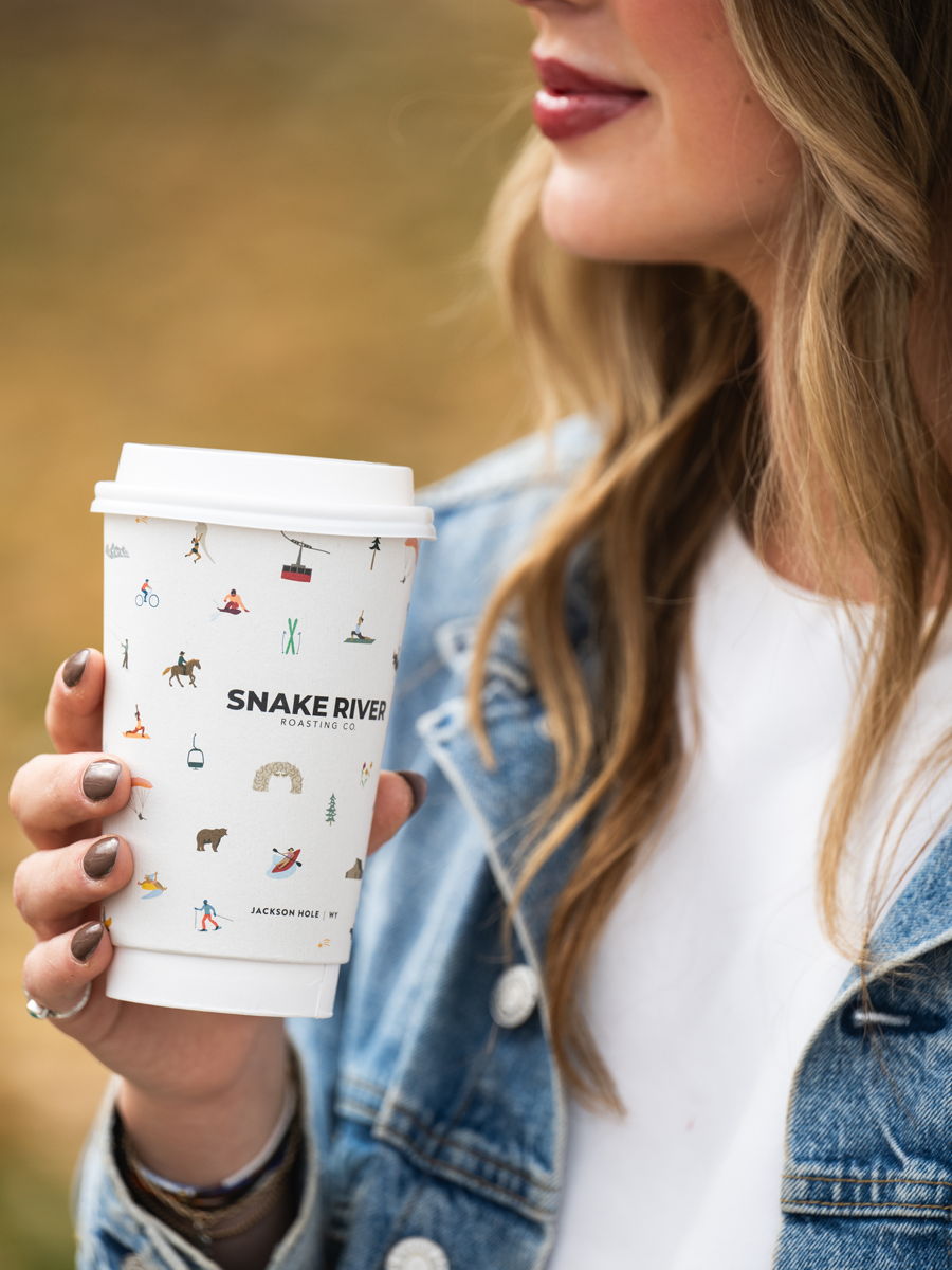 A patterned Snake River Roasting Co. cup carried through town