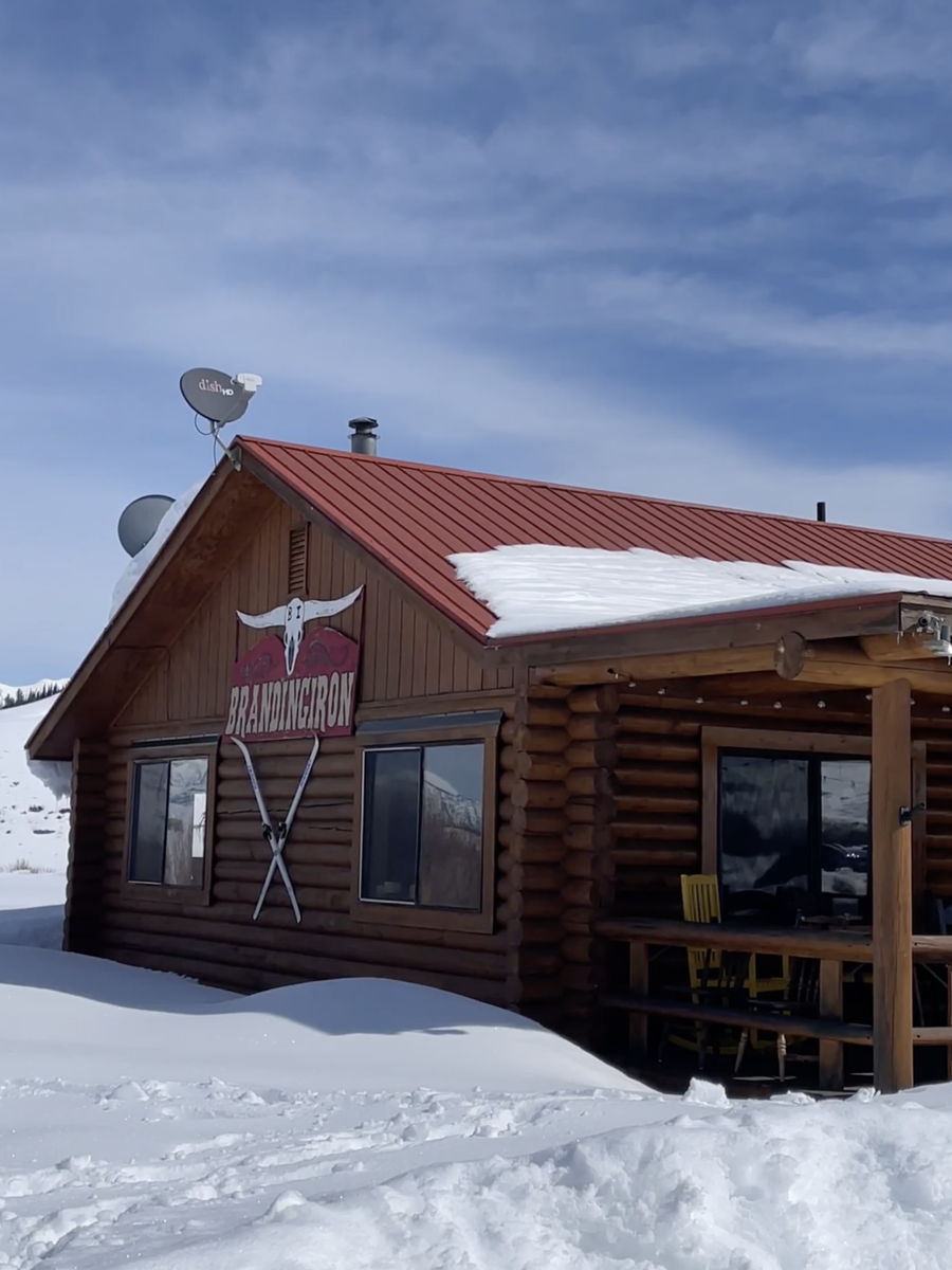 The Branding Iron log cabin in deep snow, a longhorn skull sign over the door