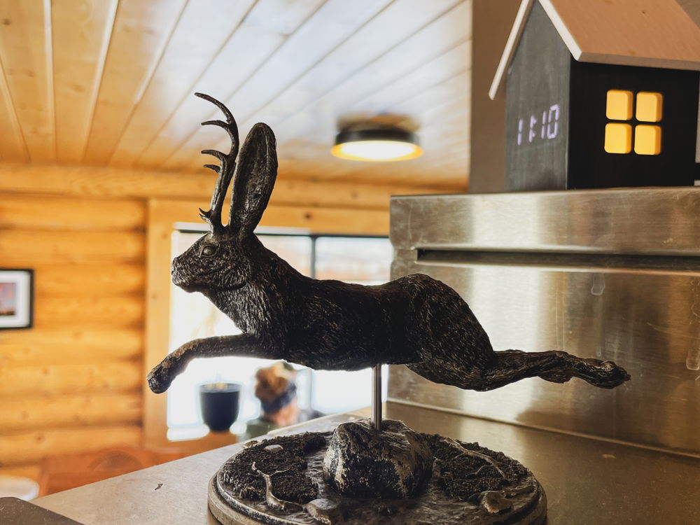 A jackalope on a shelf among tiny wooden houses