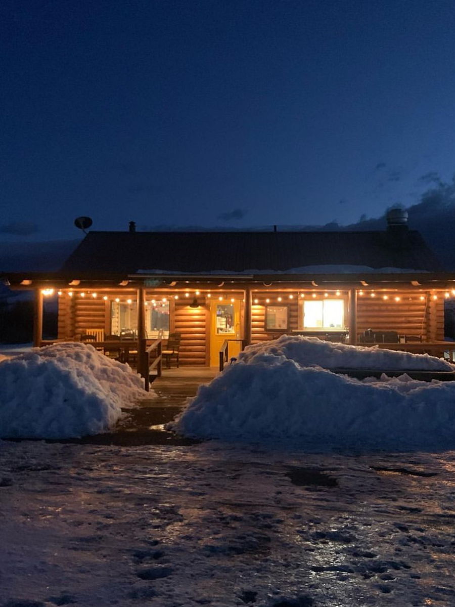 The Branding Iron cabin at night in winter, windows glowing