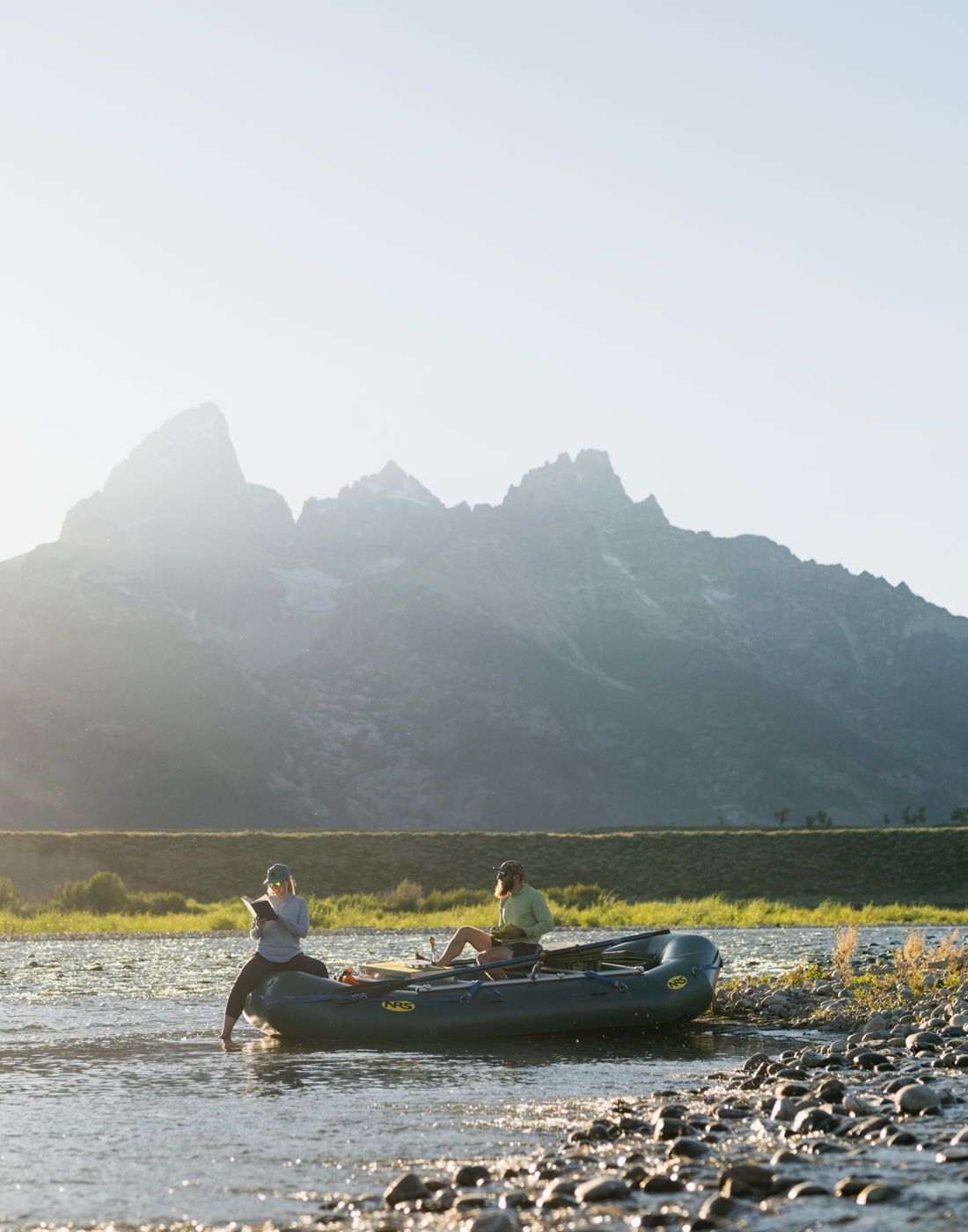 A raft floating the Snake River below the Tetons at golden hour